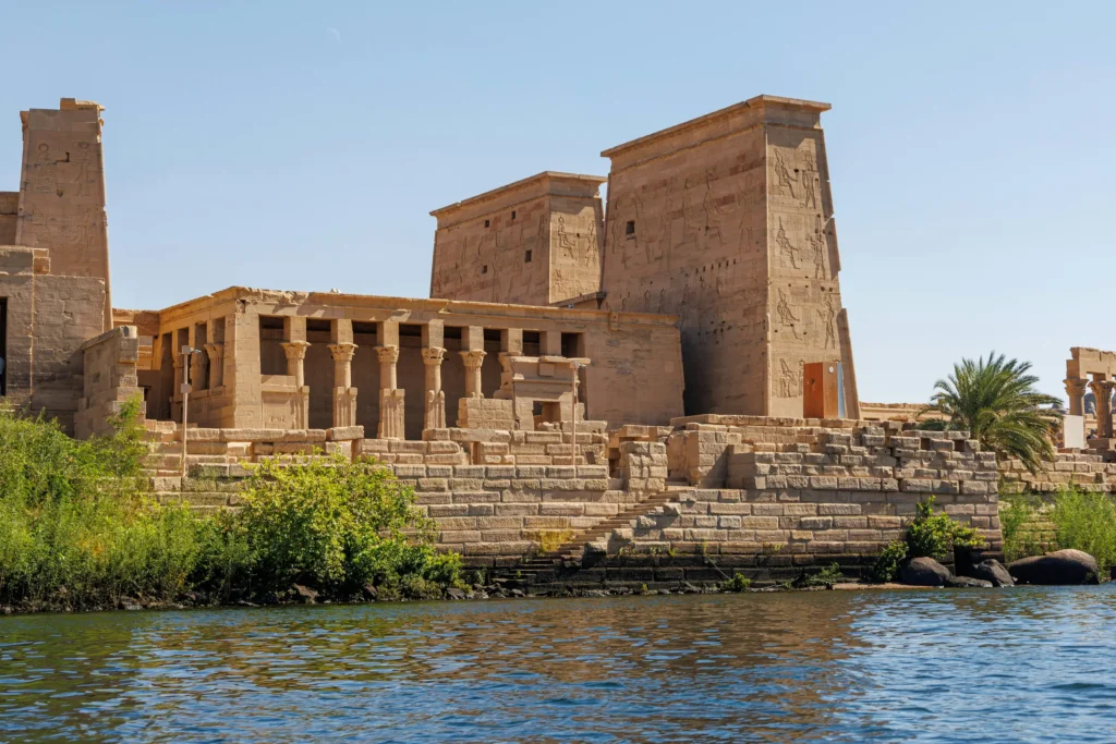 Le temple de Philae vu depuis le Nil à Assouan, son premier pylône couvert de reliefs et le portique à colonnes de l'avant-cour