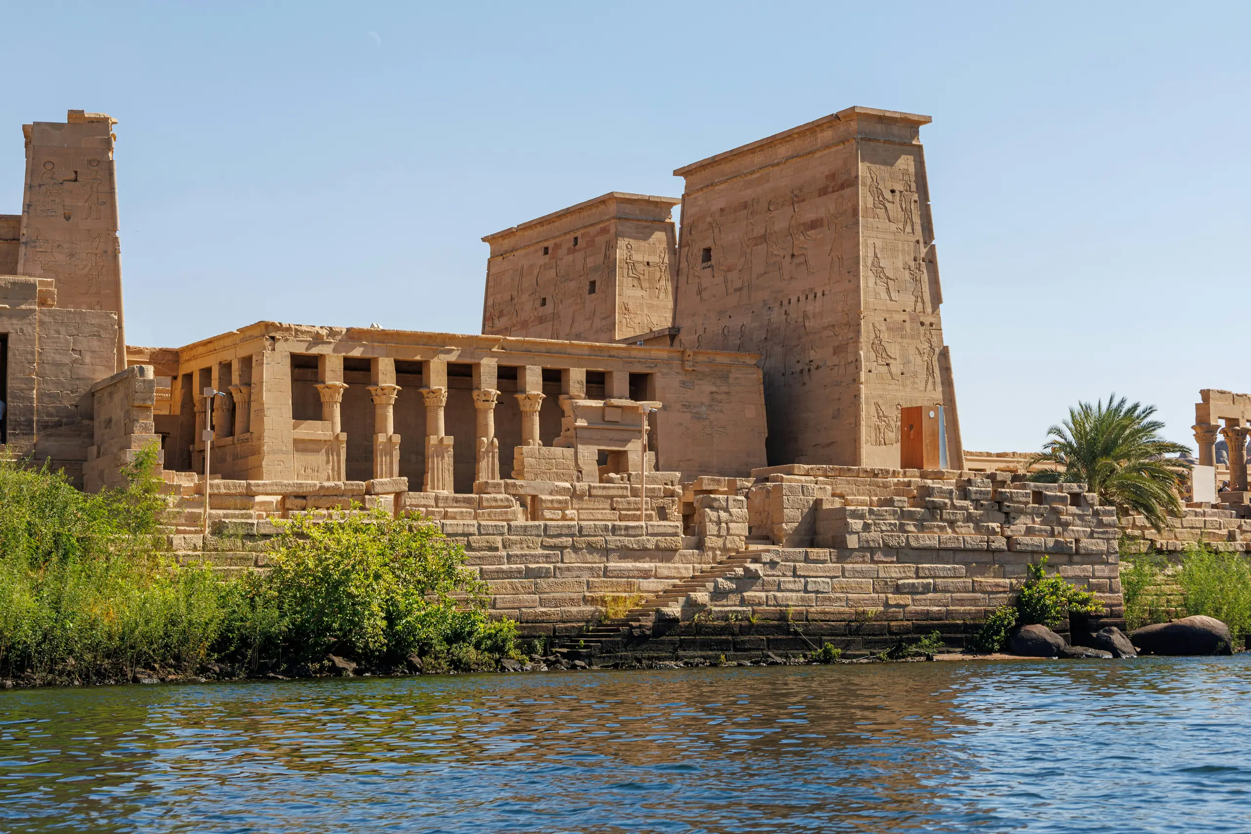 Le temple de Philae vu depuis le Nil à Assouan, son premier pylône couvert de reliefs et le portique à colonnes de l'avant-cour