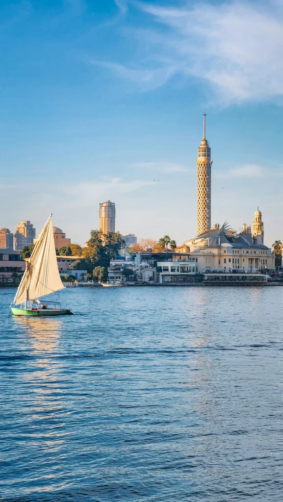 Felouque à voile blanche sur le Nil au Caire, devant la tour du Caire et l'Opéra sur l'île de Gezira, en fin de journée