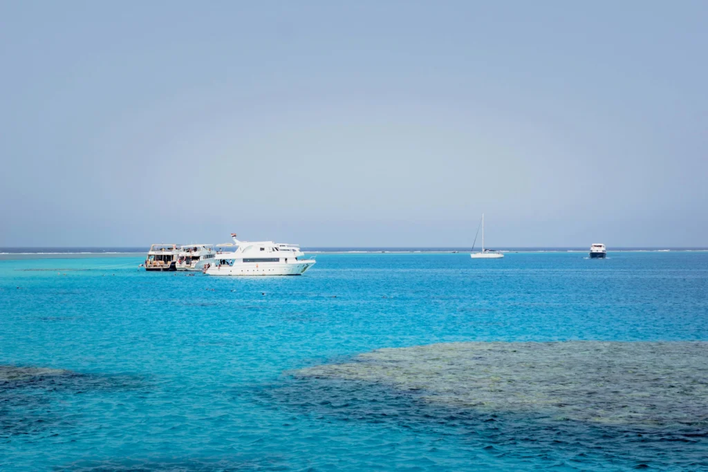 Bateaux de plongée au mouillage au bord du récif de Sataya, nageurs en surface dans l'eau turquoise de la mer Rouge
