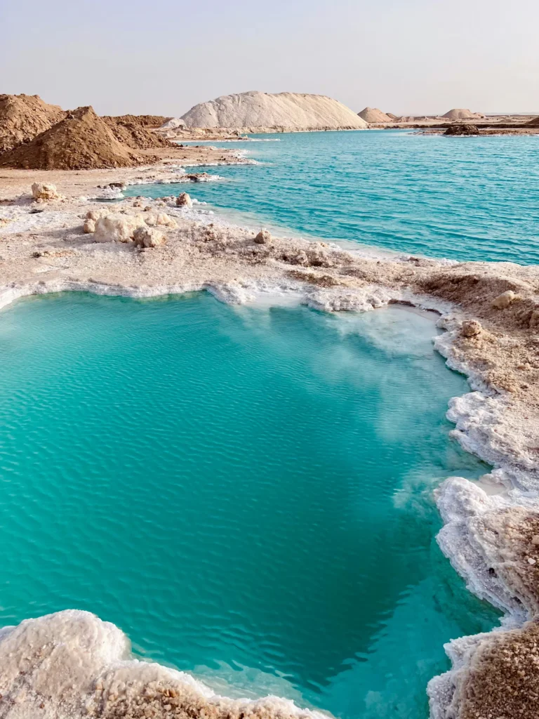 Bassins d'eau turquoise des lacs salés de Siwa, cernés de croûtes de sel blanc et de monticules en plein désert